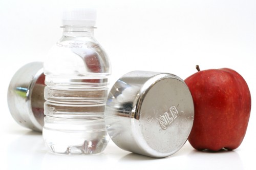 shot of a bottled water with fitness weight & apple
