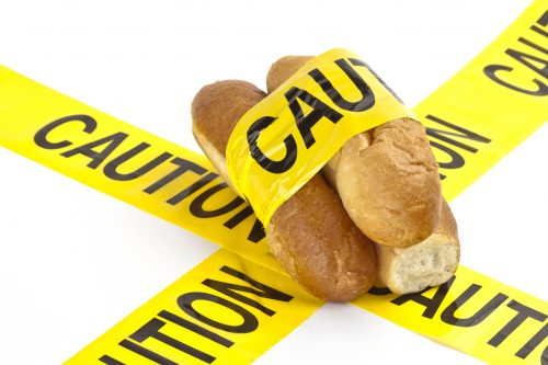 Dietary concept or gluten/wheat allergy warning (Slices of fresh French bread wrapped in yellow caution tape)
